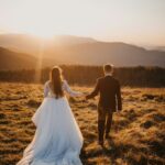 man and woman in wedding dress walking on brown grass field during daytime